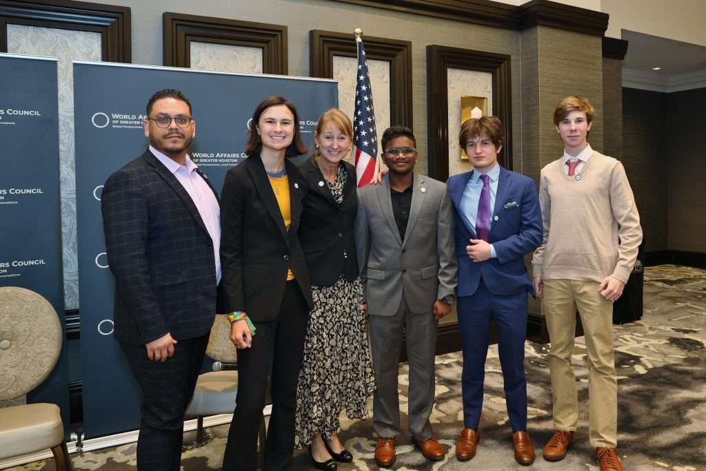 Participants posing at a World Affairs Council event, standing in front of the American flag