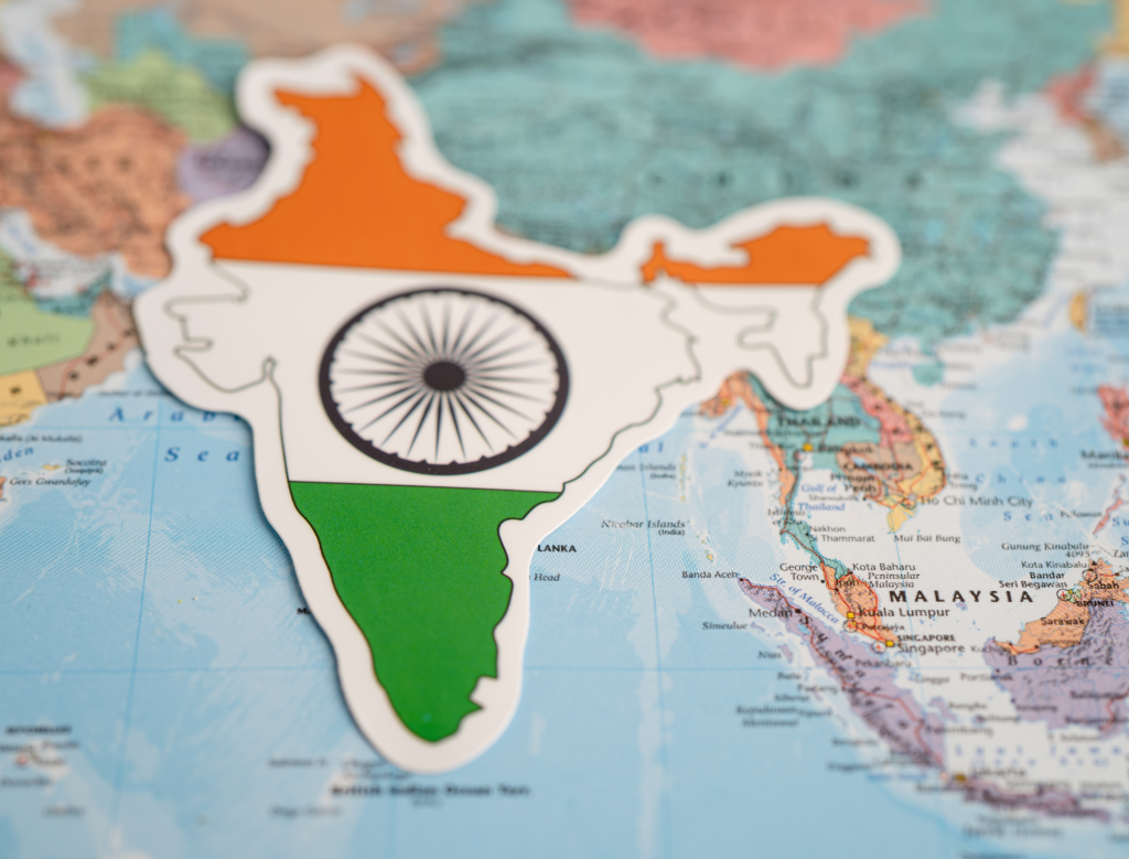 A cutout of India’s map with the Indian flag design is placed over a world map, highlighting India’s location in South Asia.